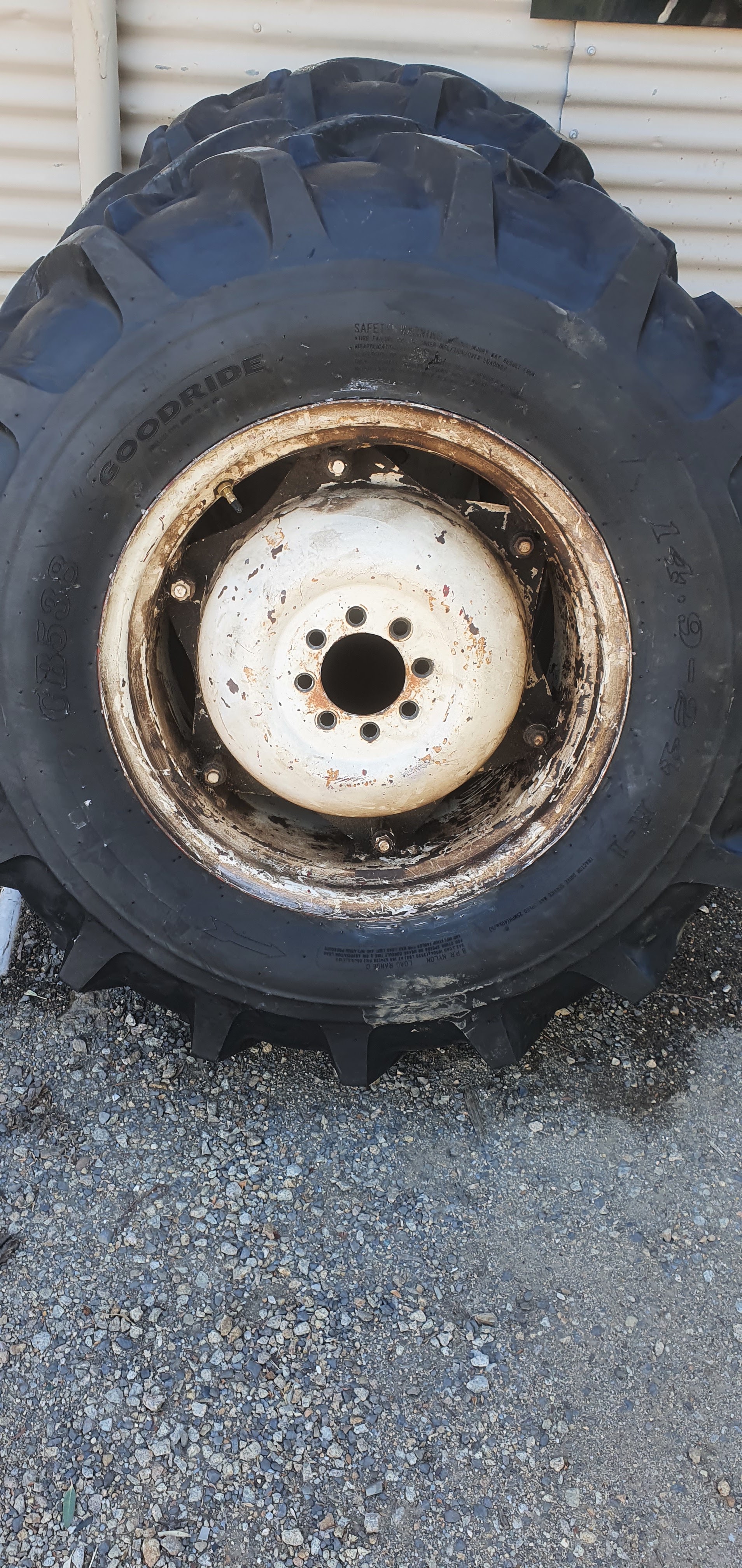 A Goodride tractor tyre mounted on a white agricultural rim outside the shed