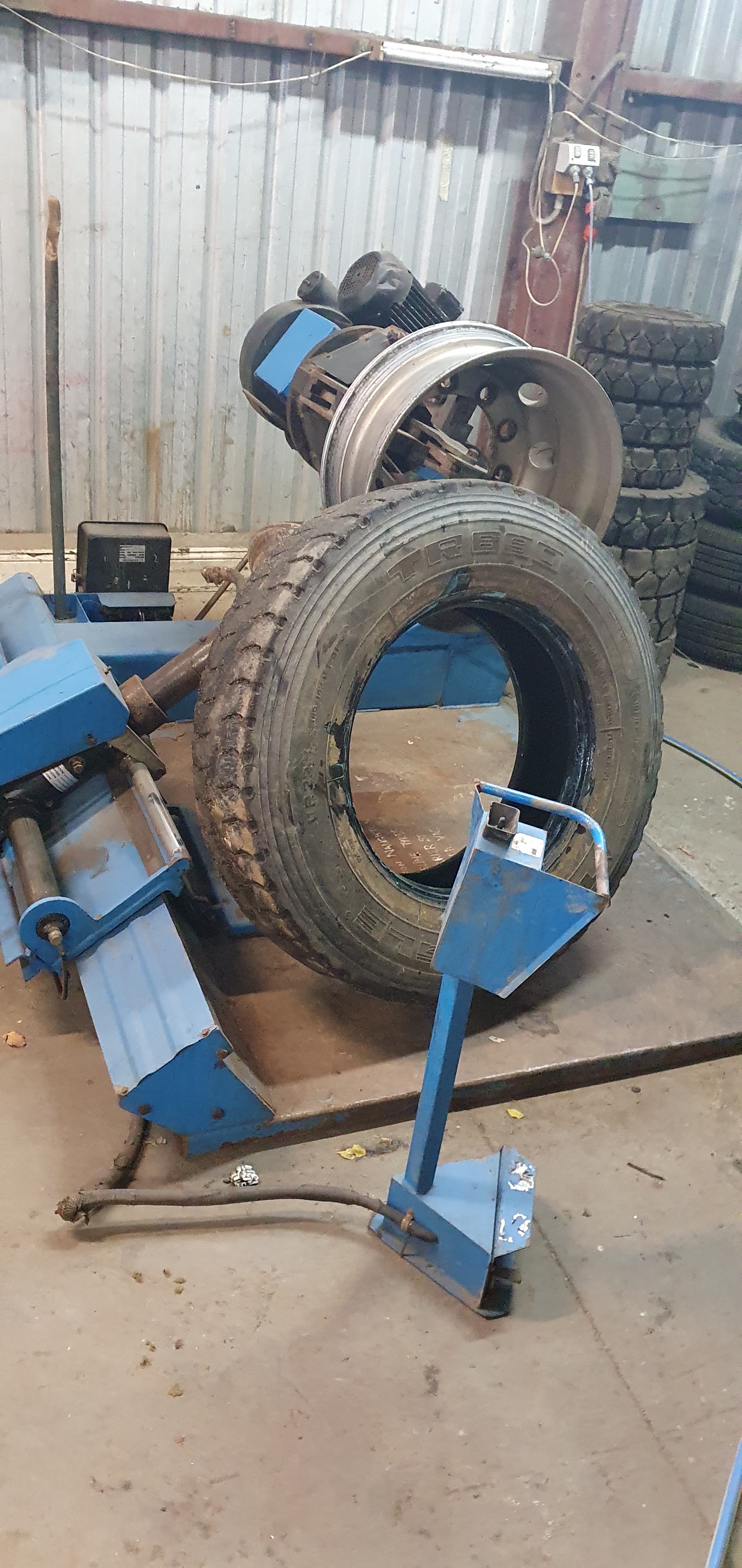 A truck tyre and steel rim on the heavy duty tyre changer at White Line Tyres