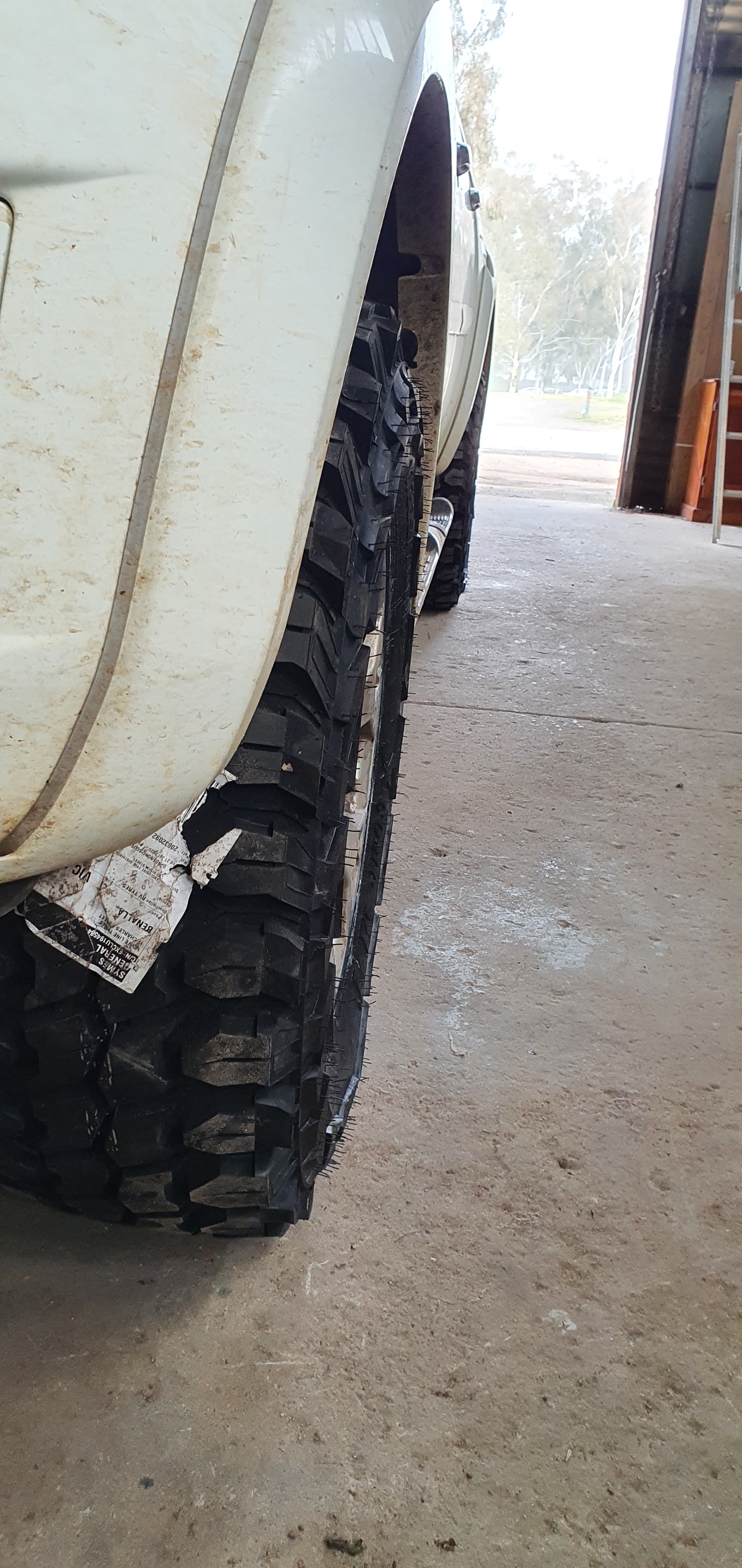 Close up of new mud terrain tyres fitted to a white four wheel drive in the workshop doorway